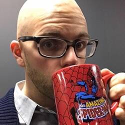 Kenny Porter, a bald man wearing glasses, drinks from a Spider-man mug.